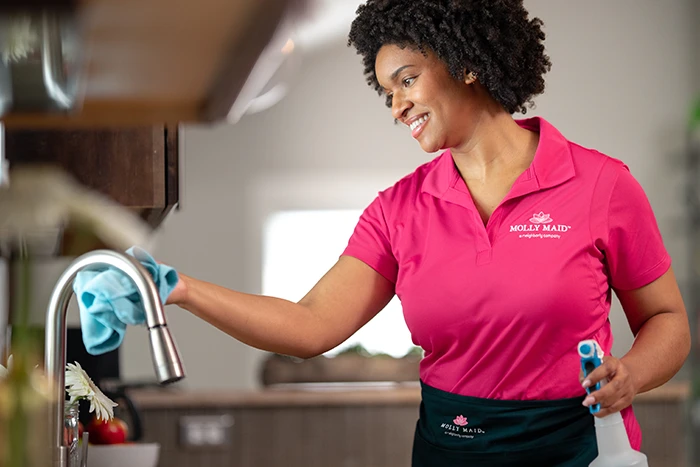 A Molly Maid professional wiping a sink during an occasional cleaning appointment.