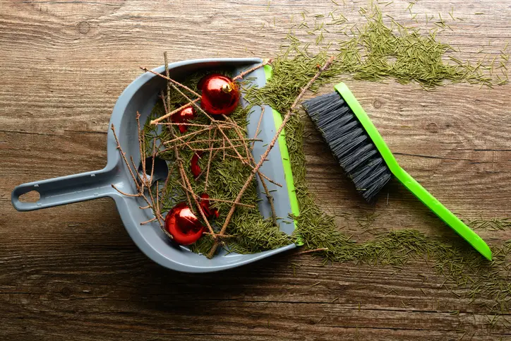 Sweeping up leftover pine needles and ornaments for post-holiday cleanup.